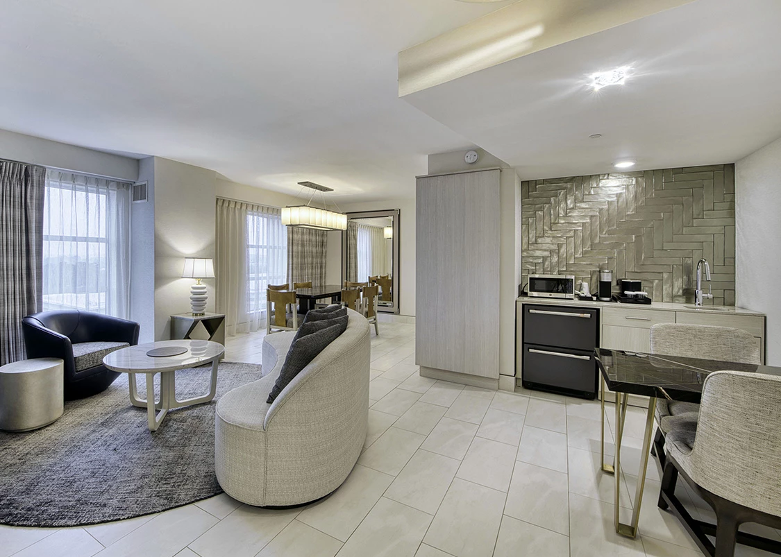 a hotel living room with a kitchen and dining area