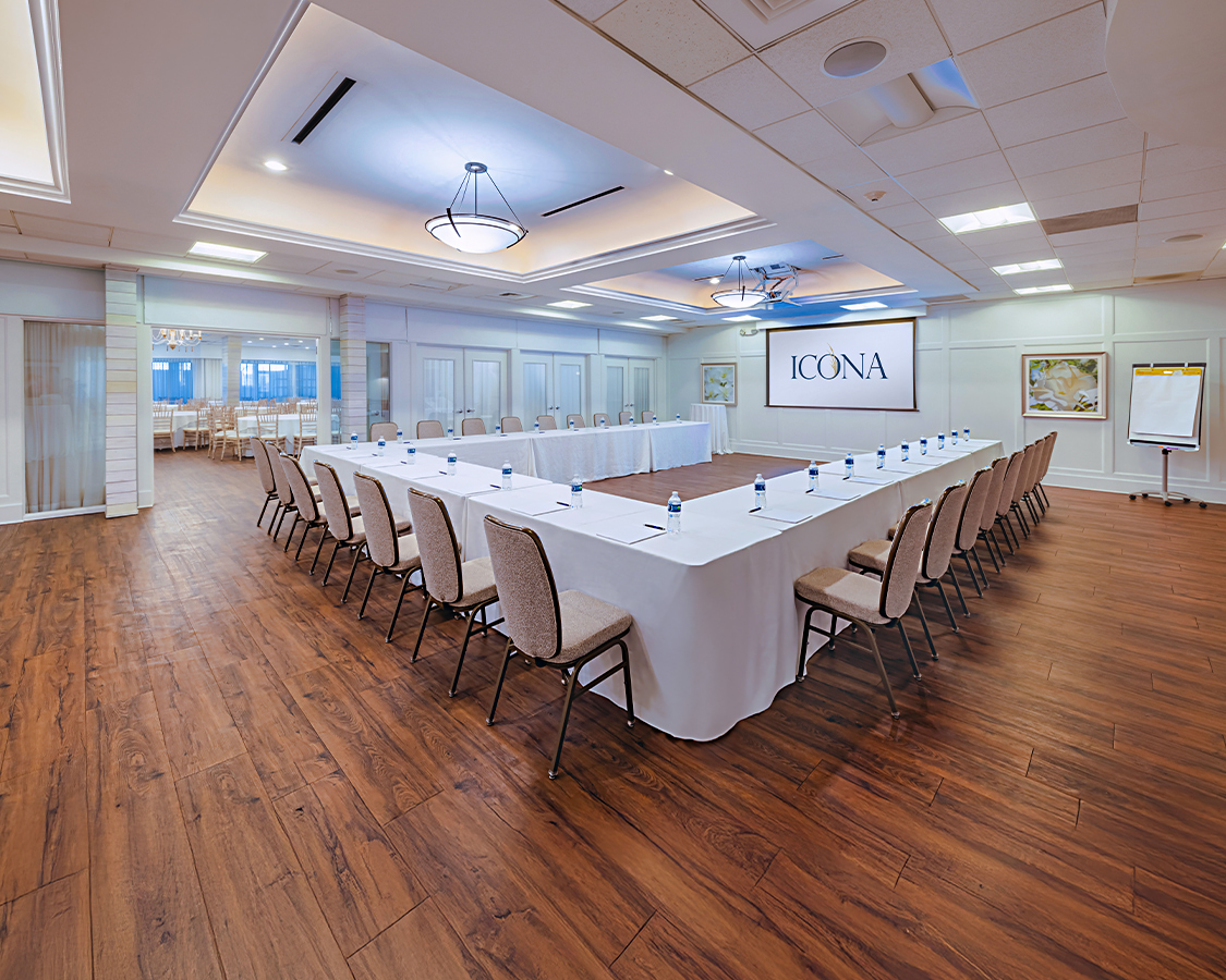 a long white table with chairs in a room with a wood floor