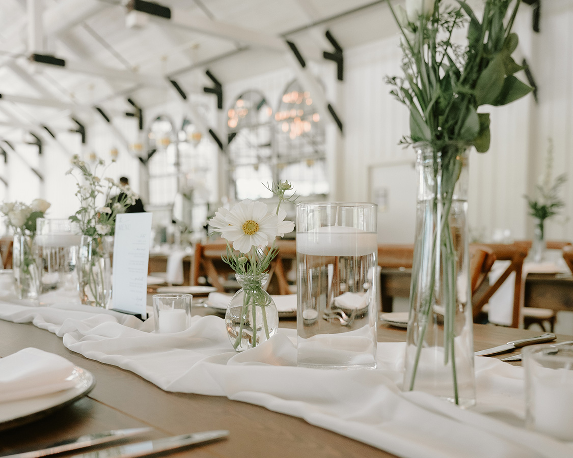 a table set with vases of water and flowers