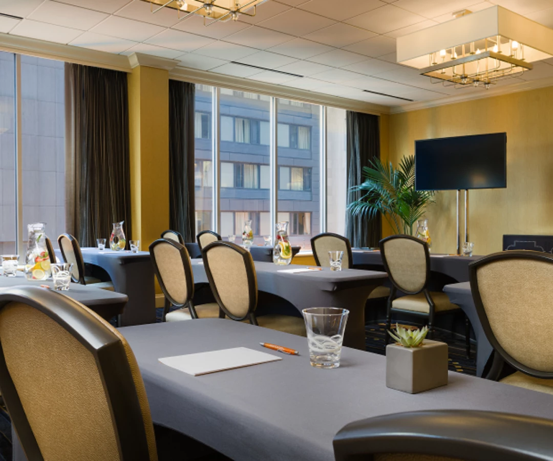 a meeting oom with tables and chairs by a window