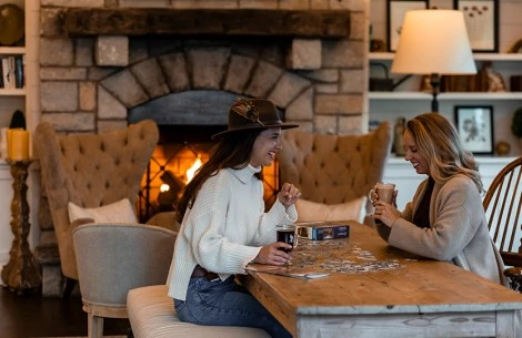 two women sitting at a table with a puzzle