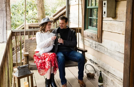a man and woman sitting on a swing with wine glasses