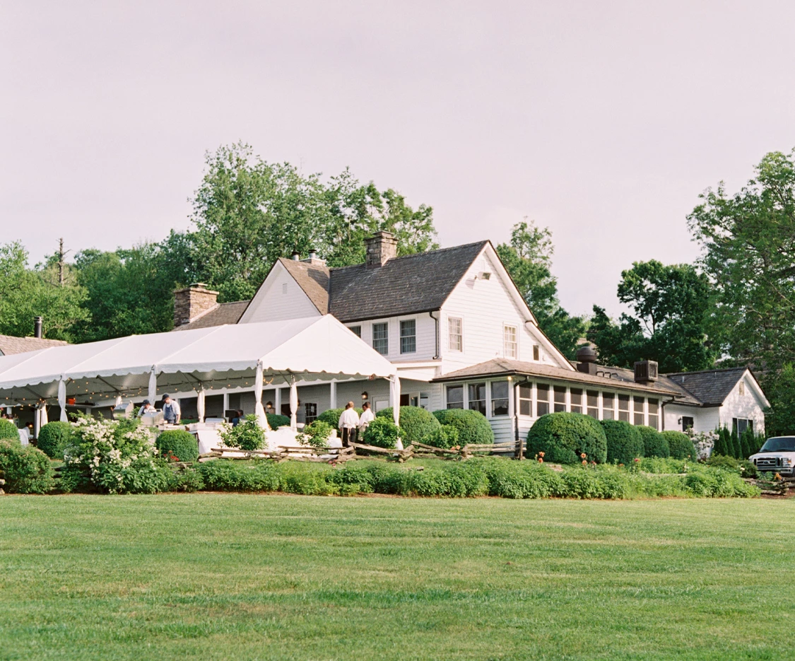 a large white house with a lawn and bushes
