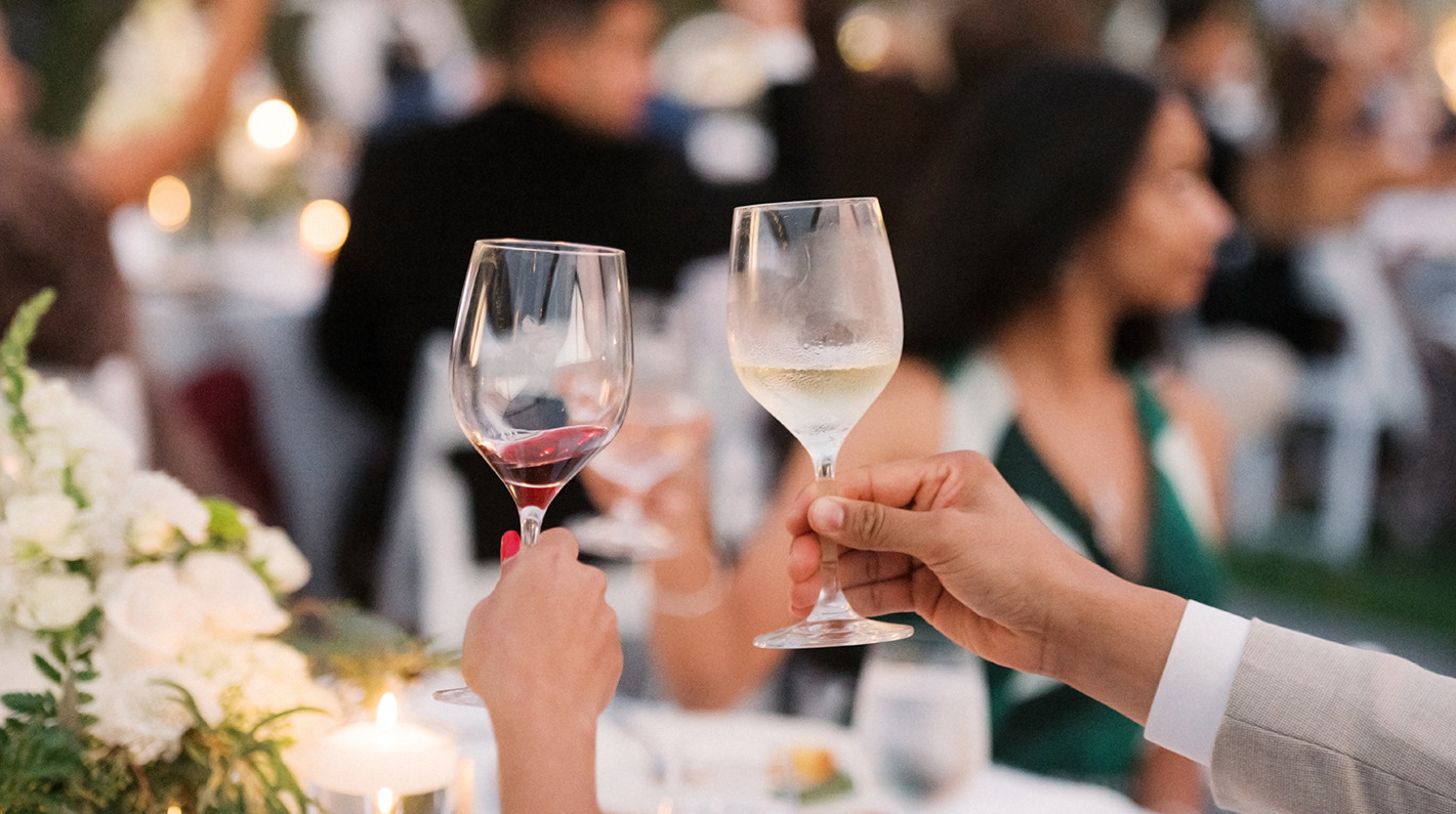 a pair of hands holding wine glasses