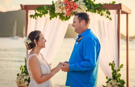 a man and woman holding hands under a floral arch