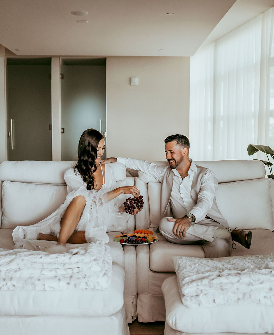 a man and woman sitting on a couch eating fruit
