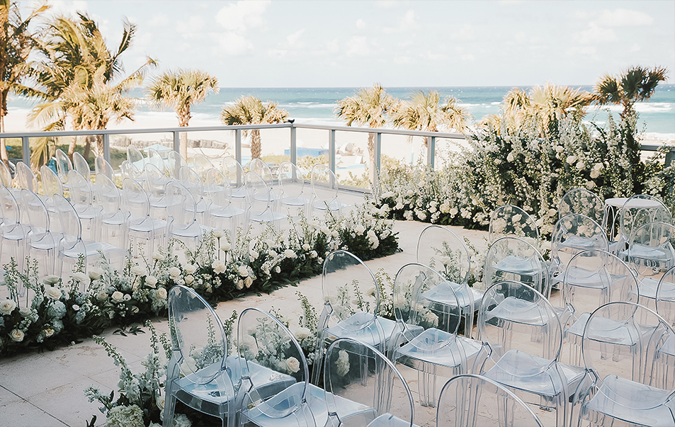 a wedding ceremony with clear chairs and flowers