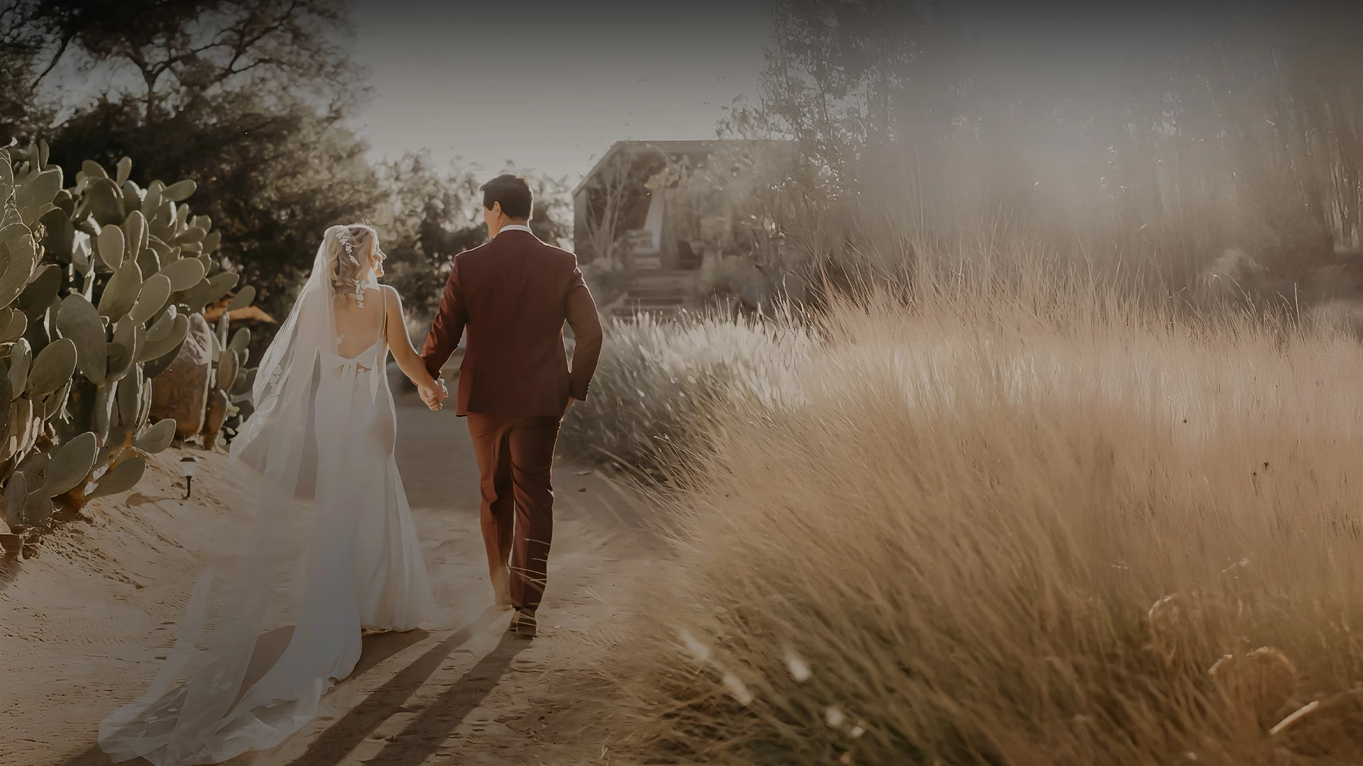 a man and woman holding hands walking down a path