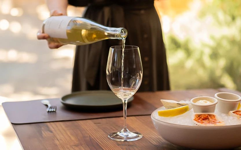 a person pouring a wine into a glass