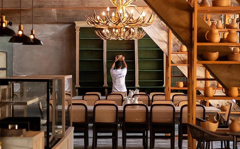 a man standing in a room with chairs and a chandelier