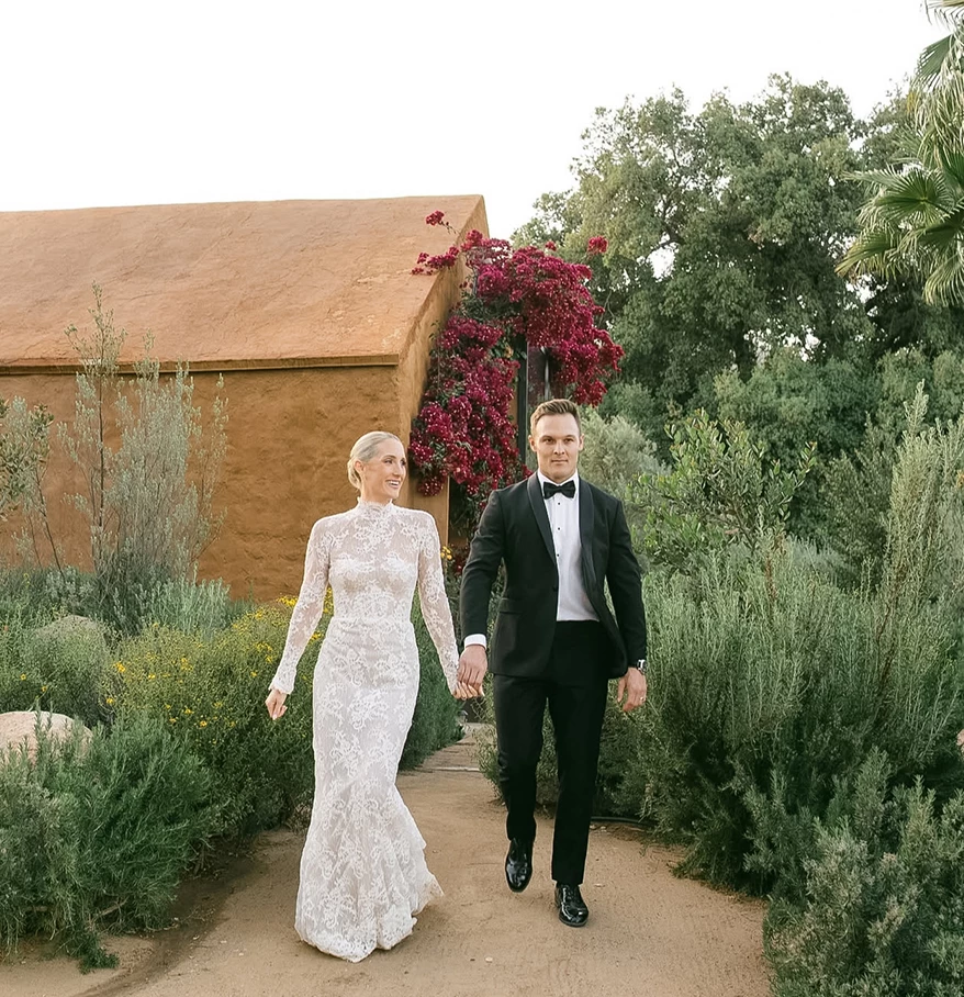 a man and woman in wedding attire holding hands and walking