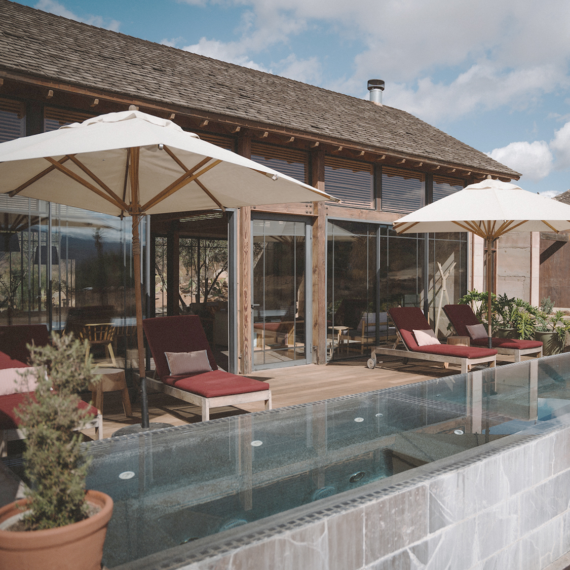 a pool with umbrellas and chairs outside of a building