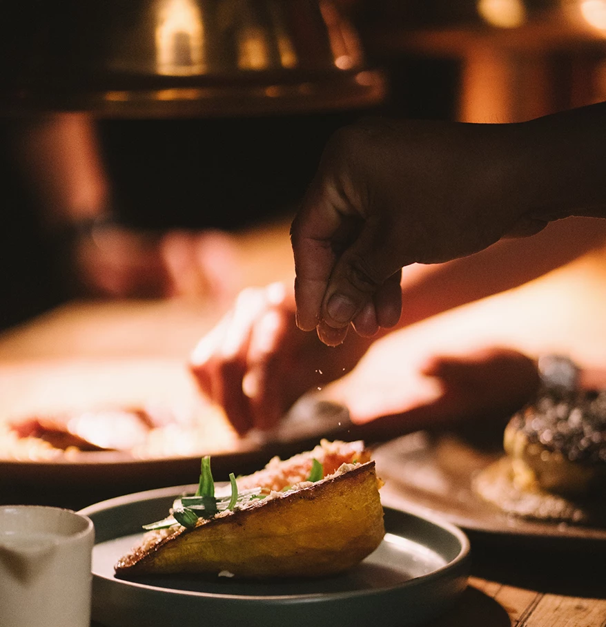 a person's hand sprinkling food on a plate