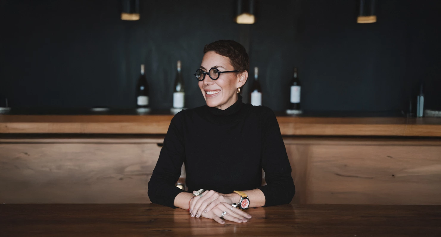 a woman sitting at a table with her hands folded