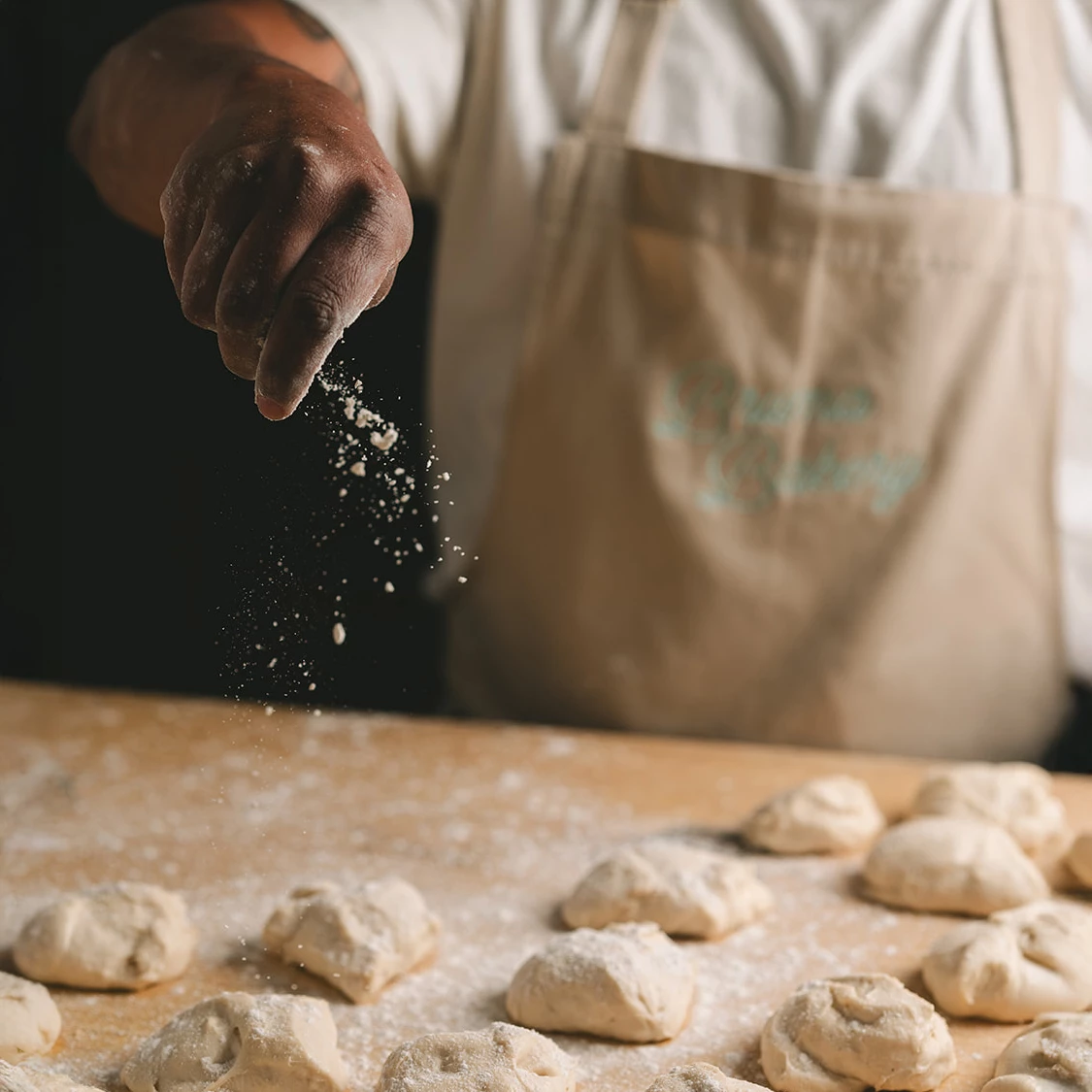 a person sprinkling flour on dough