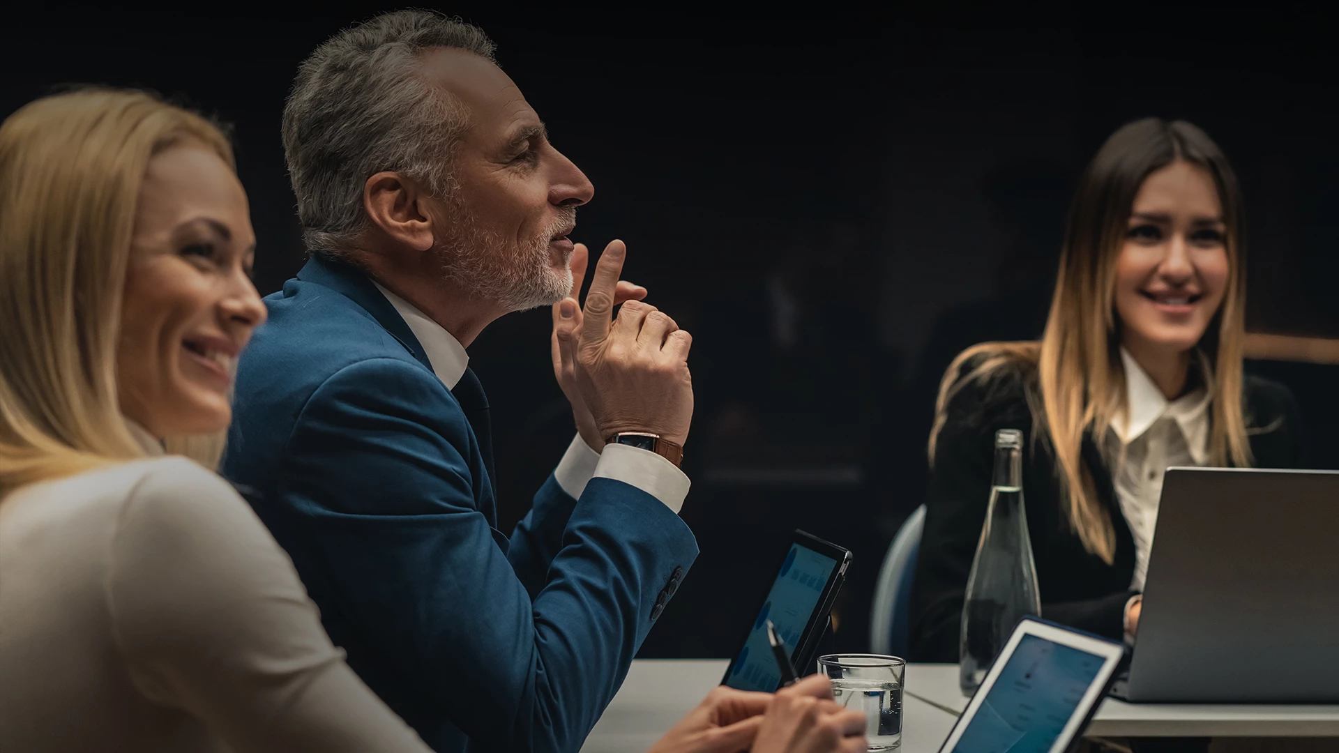 a man in a suit sitting at a table with a woman in a dark room