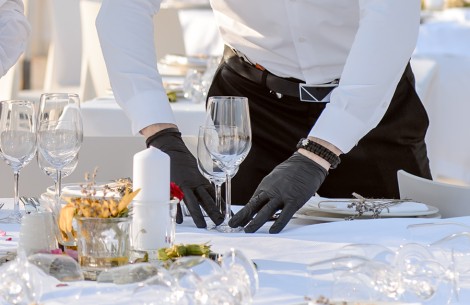 a man wearing gloves and holding a wine glass