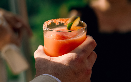 a hand holding a glass of orange drink