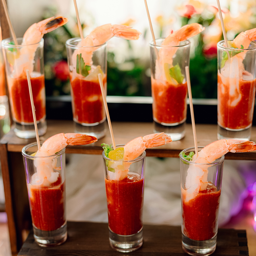 a group of glasses of shrimp with sauce on a wooden table