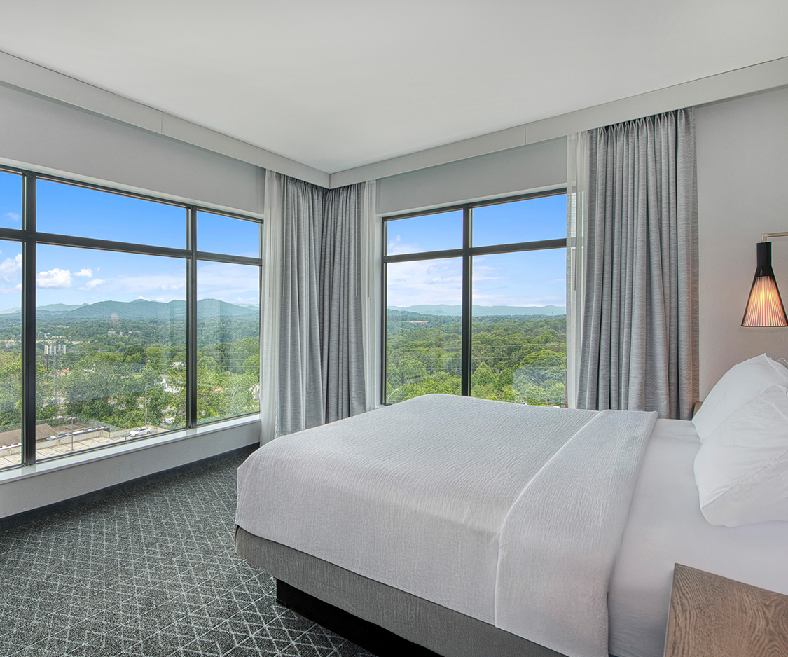 a bedroom with large windows and a view of the city
