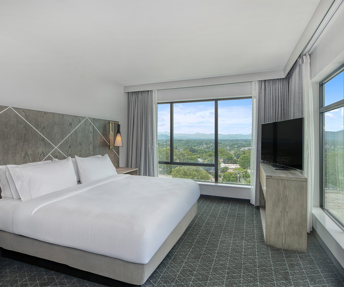 a bedroom with a large window and a large bed