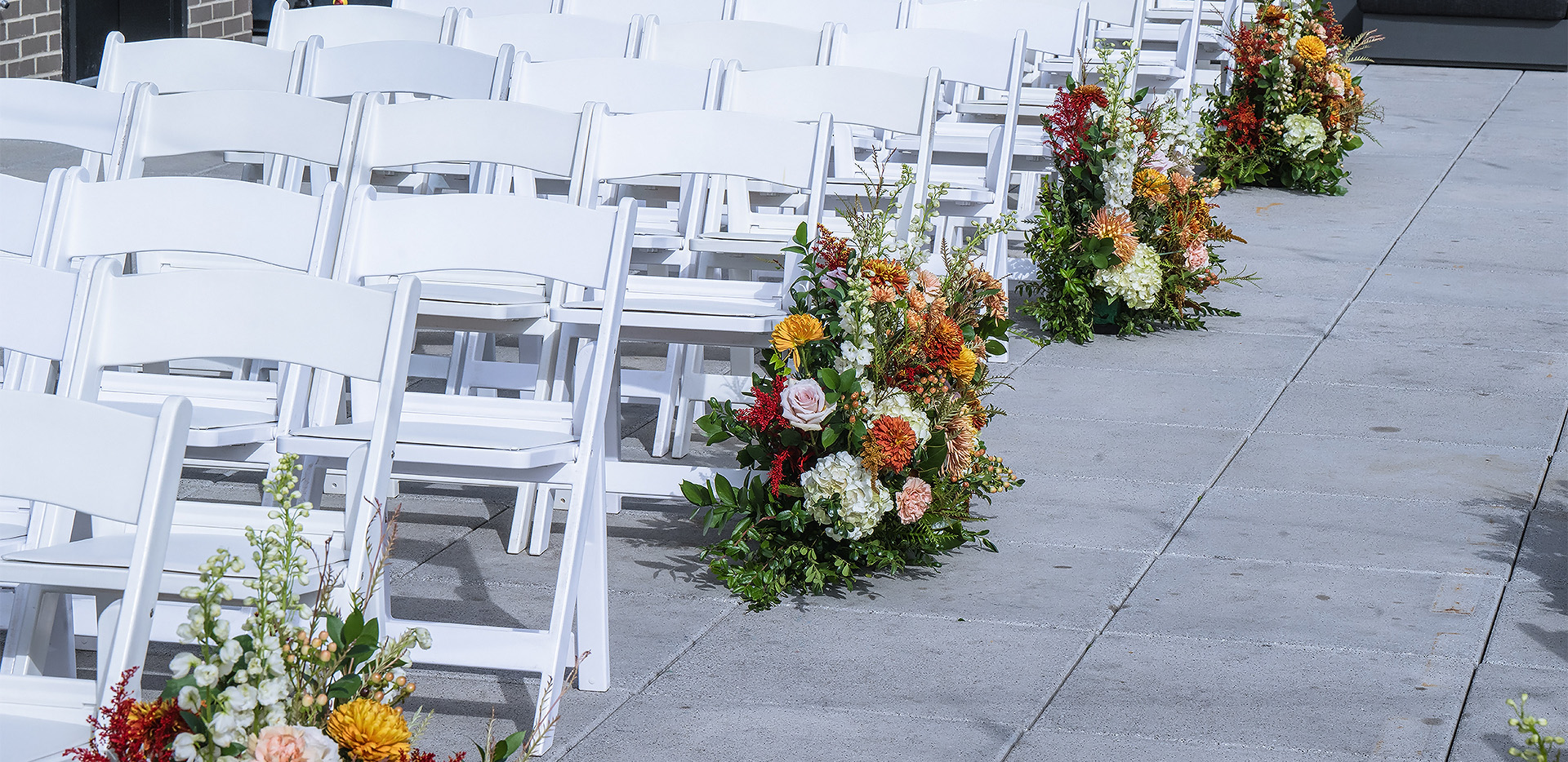 a row of white chairs with flowers