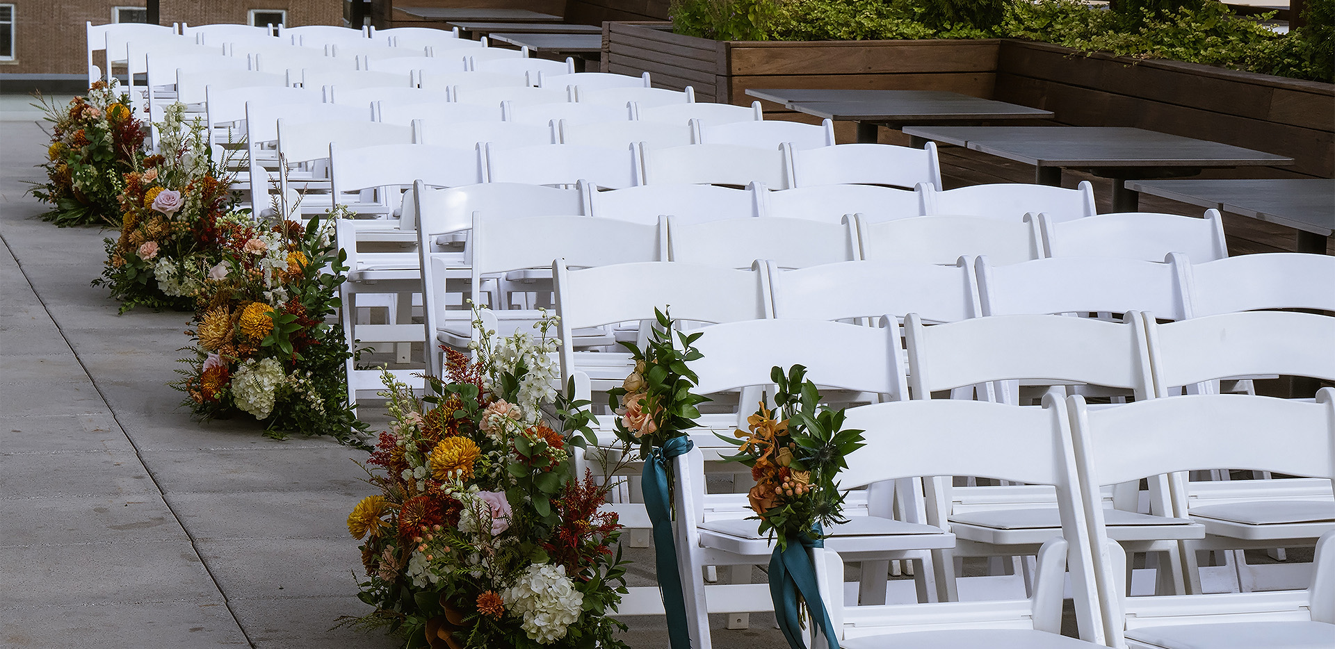 rows of white chairs with flowers
