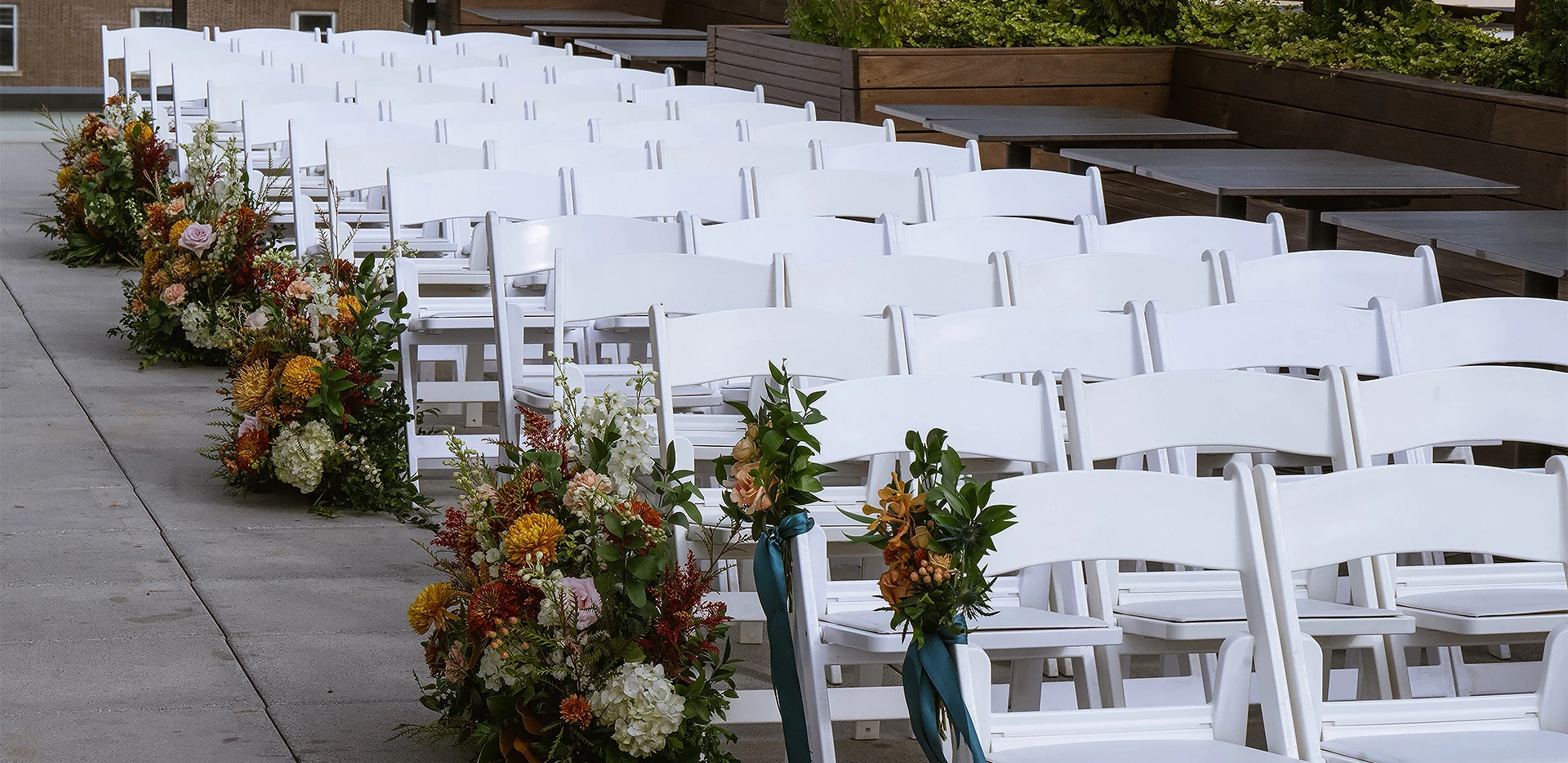 rows of white chairs with flowers