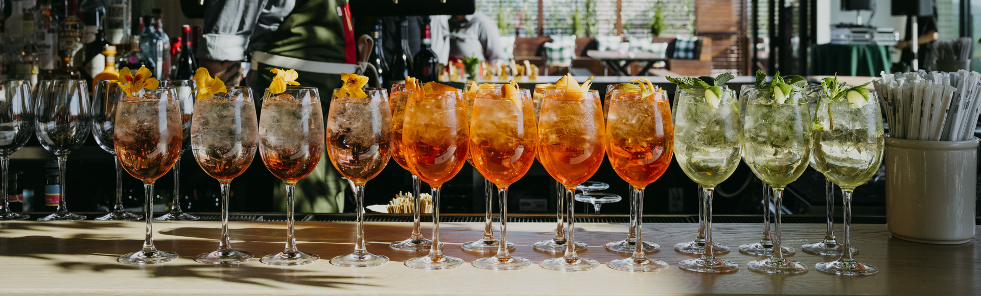 a row of glasses with orange liquid and ice