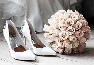 a pair of white shoes with a bouquet of flowers