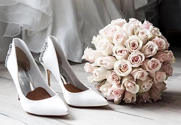 a pair of white shoes with a bouquet of flowers