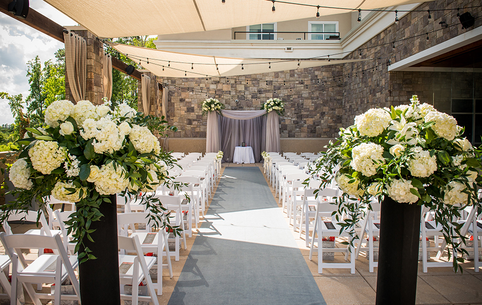 a wedding ceremony with white chairs and flowers