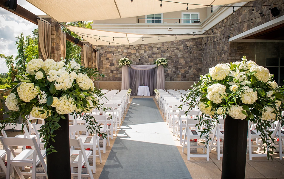 a wedding ceremony with white chairs and flowers