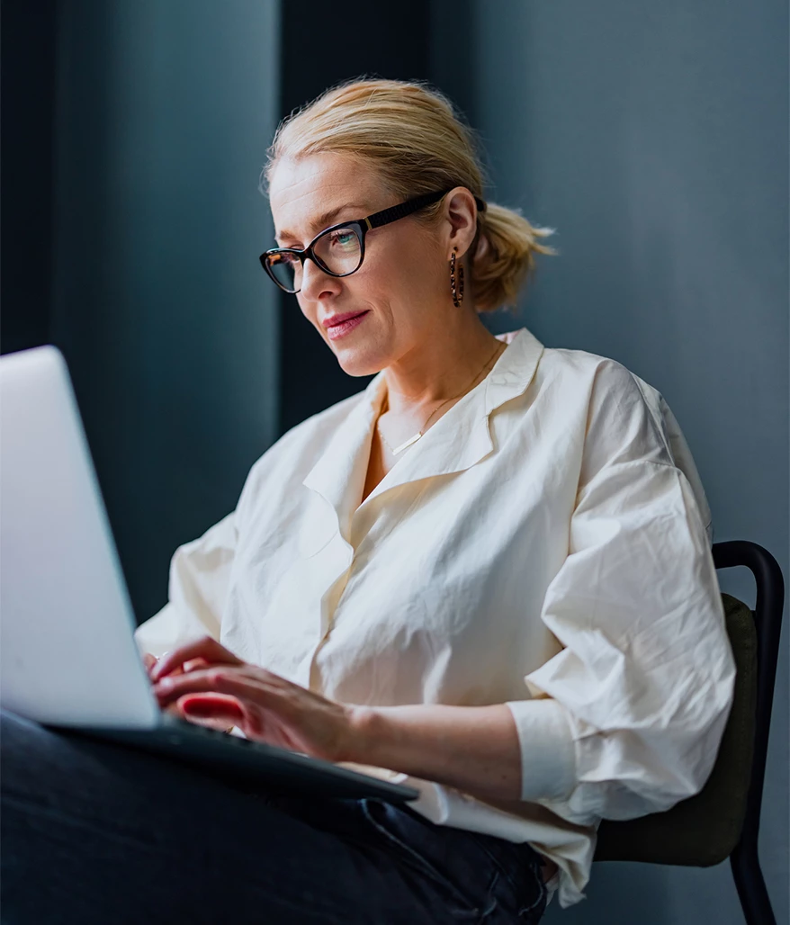a woman sitting in a chair using a laptop