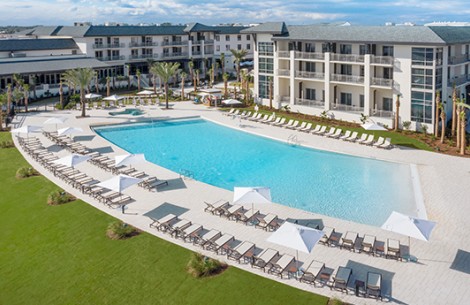a pool with lounge chairs and umbrellas in front of a hotel