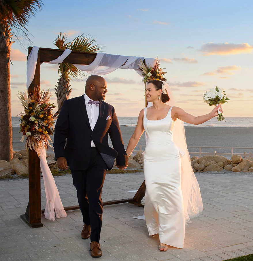 a man and woman holding hands and walking down a walkway