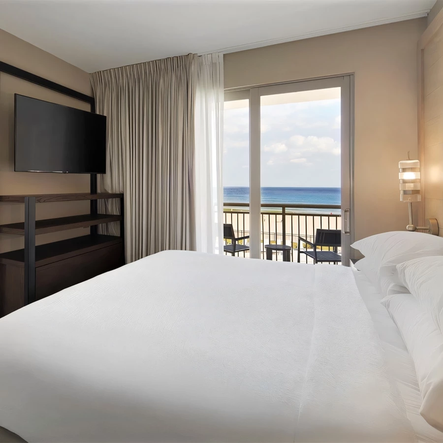 a bed with a television and a balcony overlooking the ocean