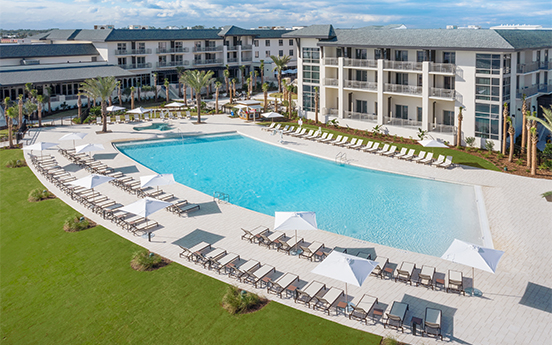 a pool with lounge chairs and umbrellas in front of a hotel