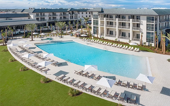 a pool with lounge chairs and umbrellas in front of a hotel