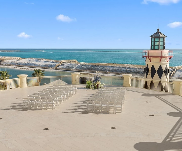 a white chairs on a patio with a lighthouse and a blue sky