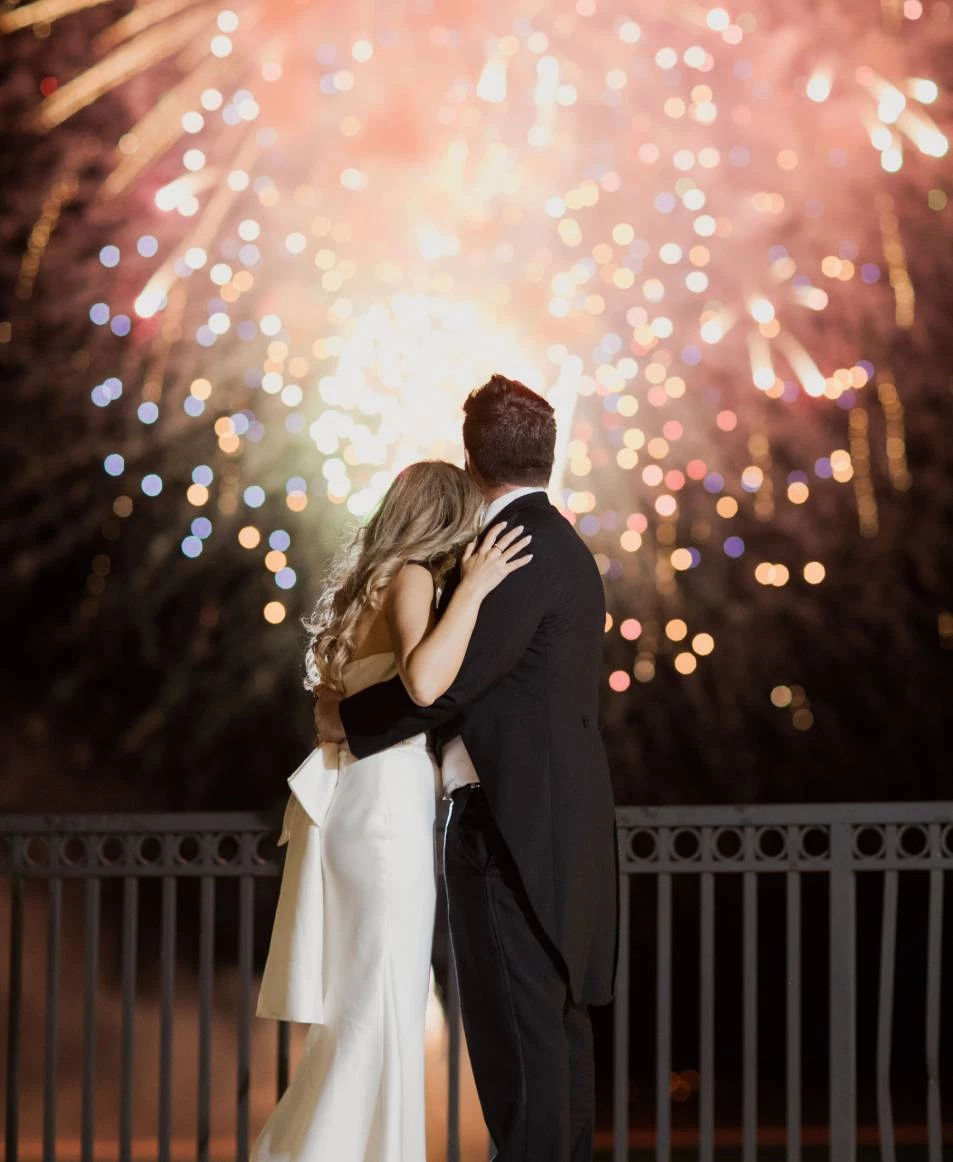 a man and woman hugging in front of fireworks