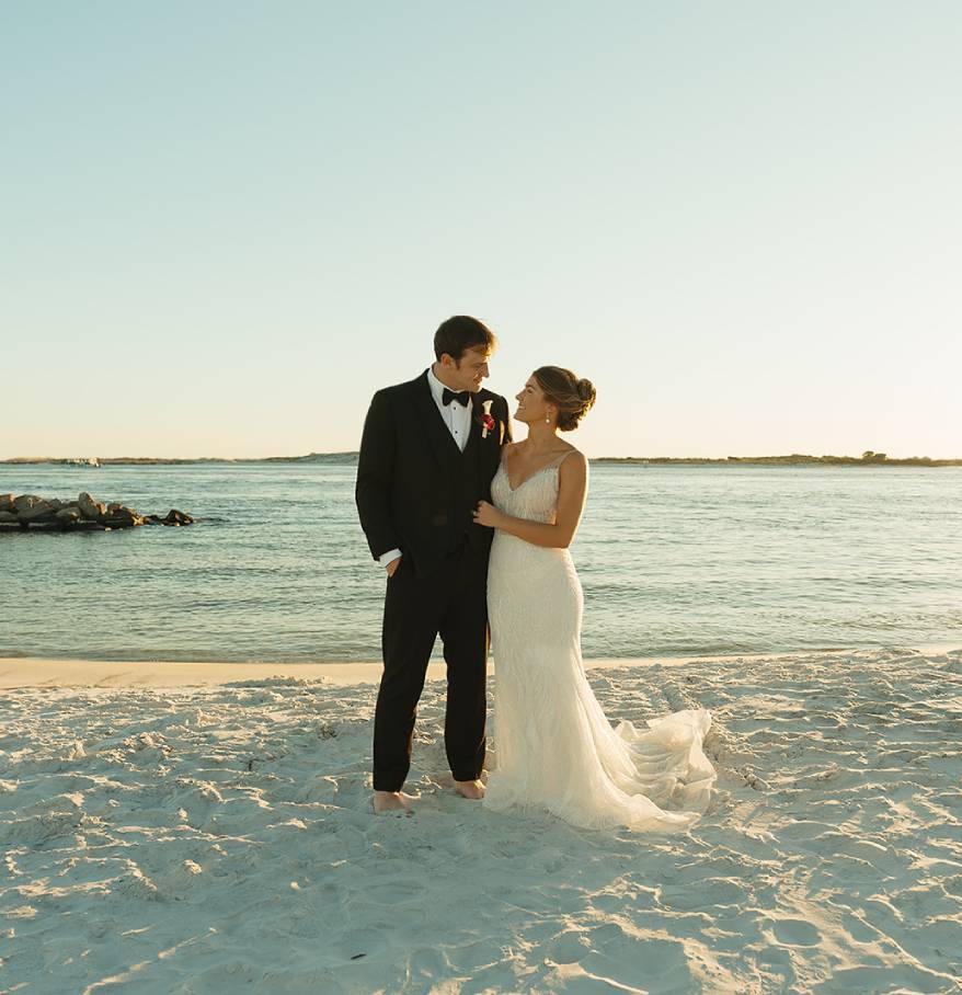 a man and woman in wedding attire on a beach