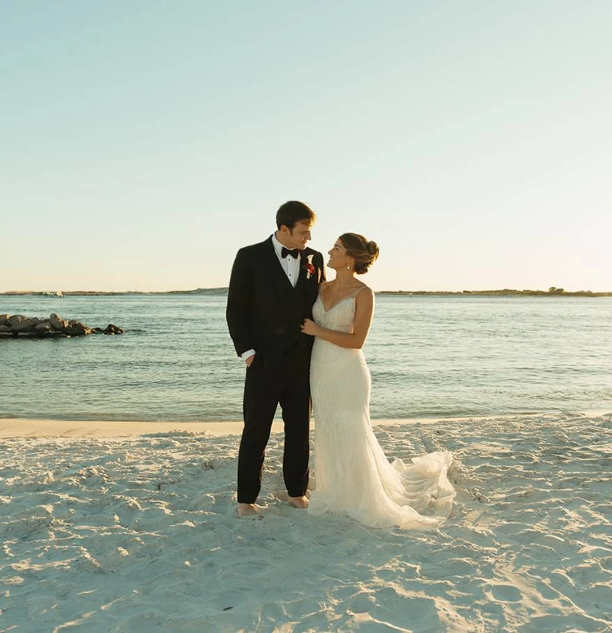 a man and woman in wedding attire on a beach