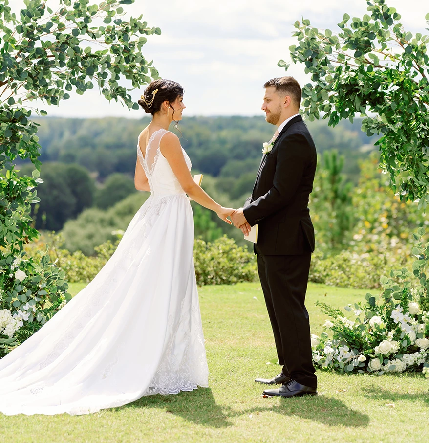 a bride and groom holding hands in a garden