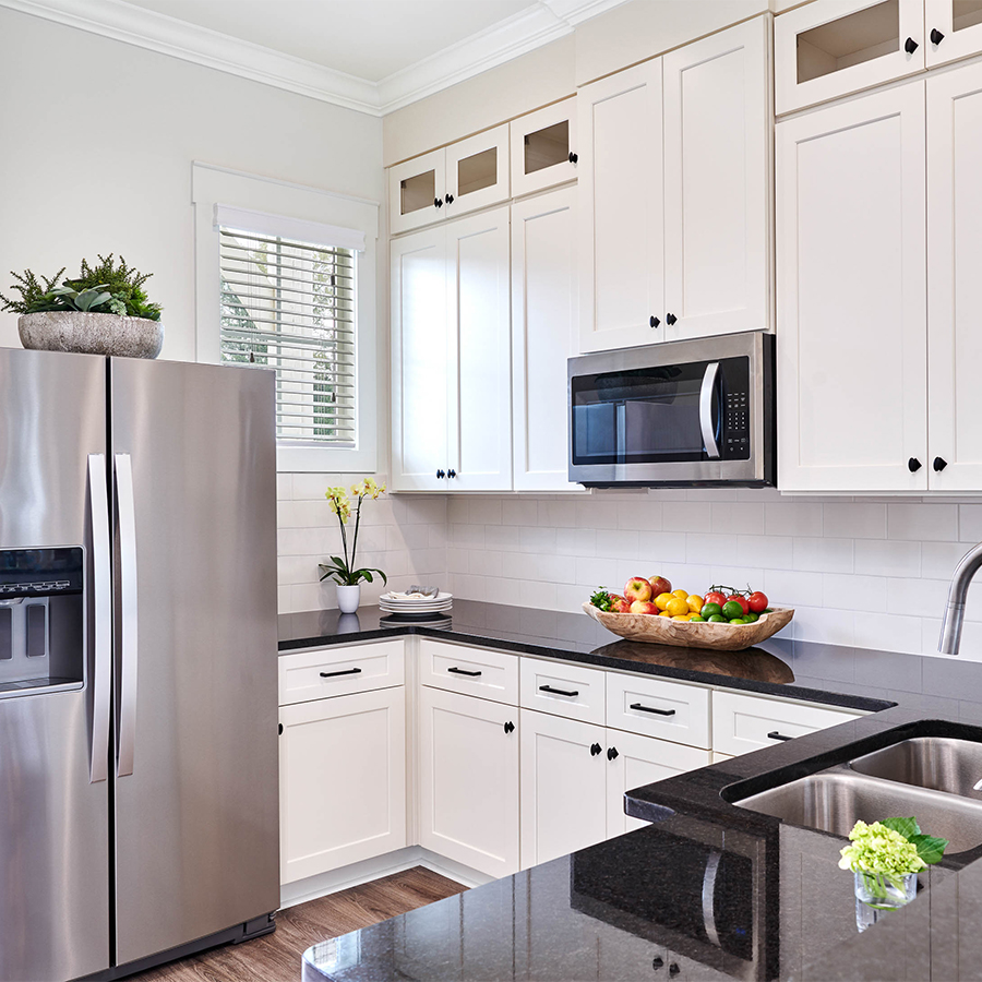 a kitchen with white cabinets and black counter tops
