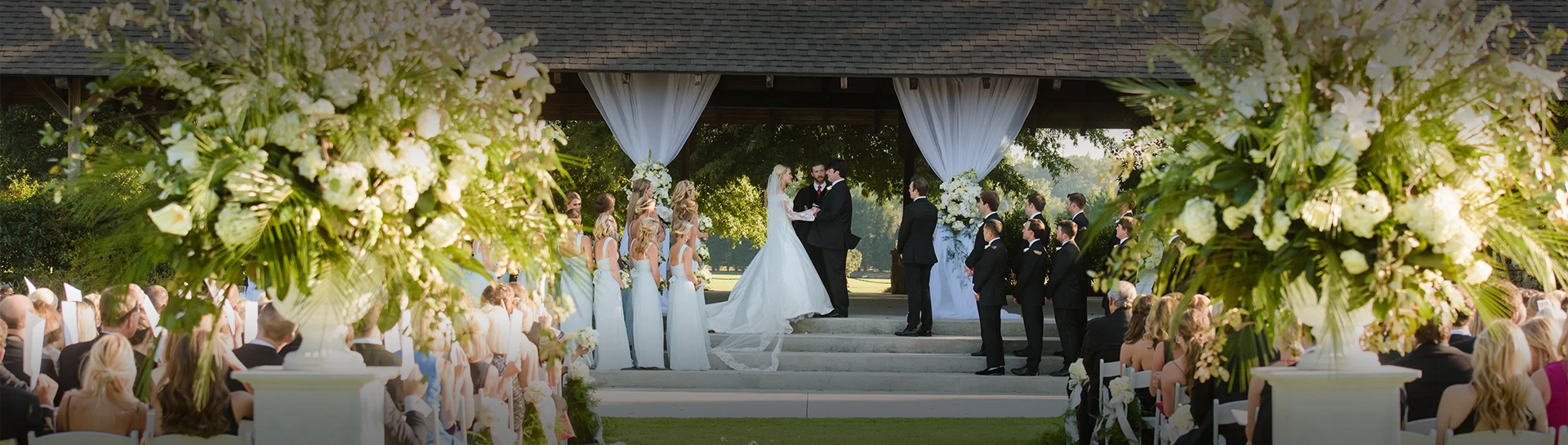 a bride and groom standing on stairs outside with a group of people