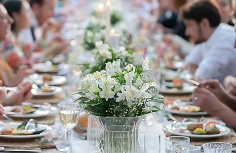 a group of people sitting at a table with flowers