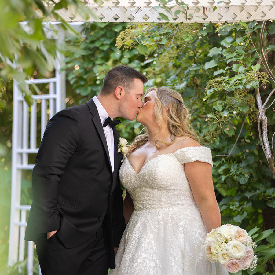 a man and woman kissing under a arbor