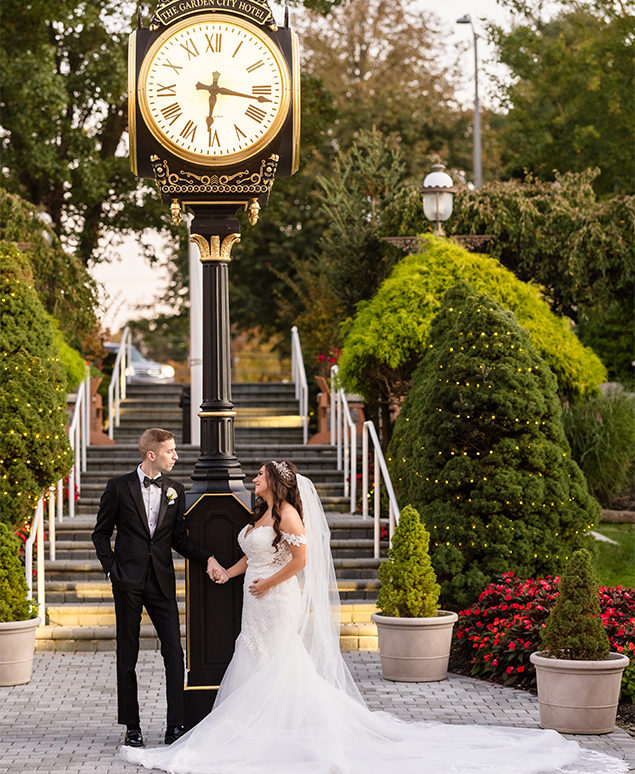 a bride and groom holding hands in front of a clock