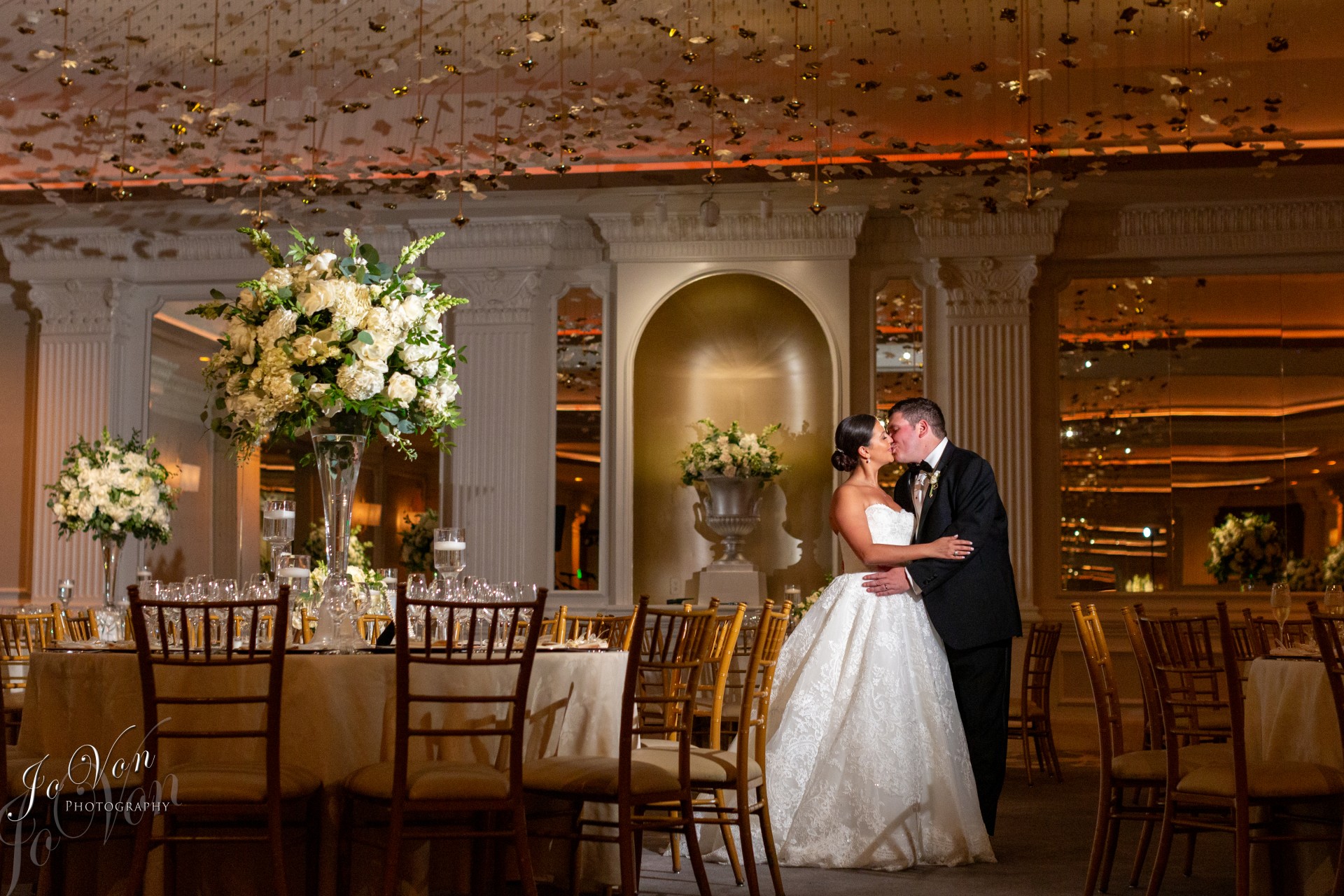 a bride and groom kissing in a room with tables and chairs